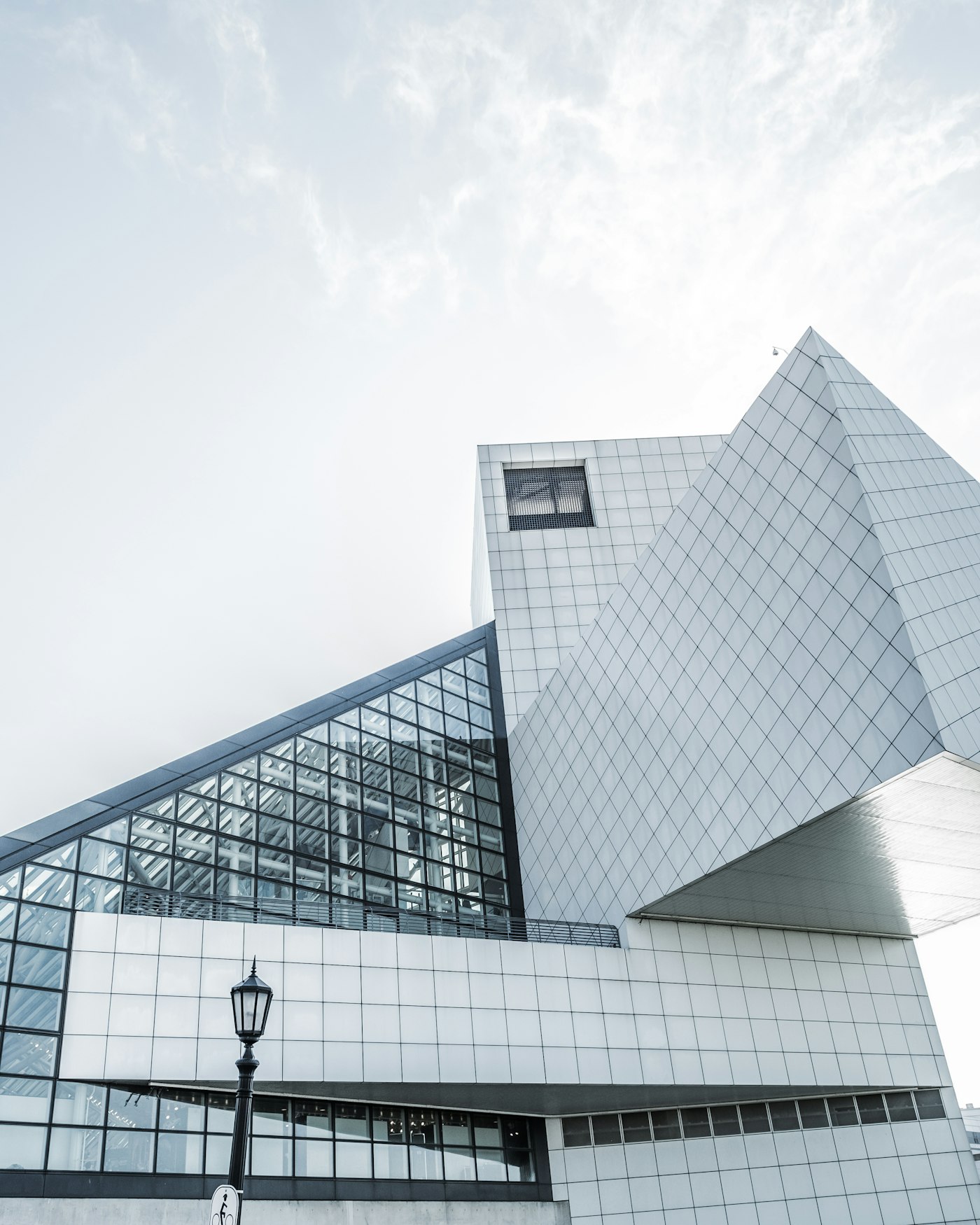 A tiled white tower and a sloped glass atrium meeting at sharp angles