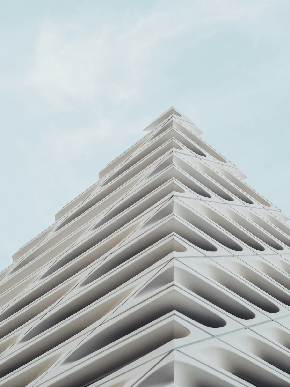A white honeycomb facade rising to a point against a hazy sky