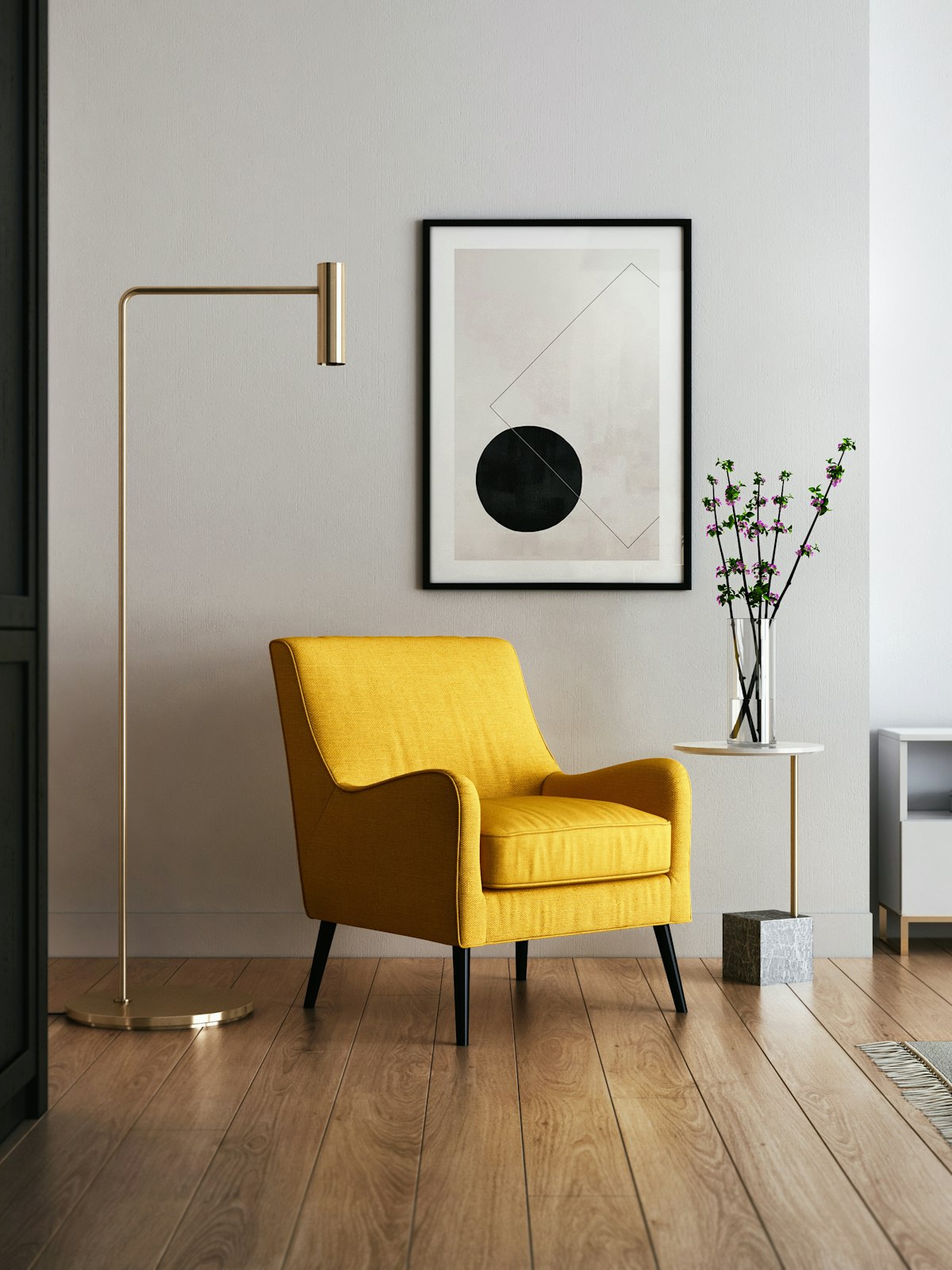 A mustard armchair and brass floor lamp in a pale, sparse living room